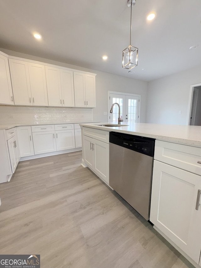 kitchen with light wood-style flooring, a sink, hanging light fixtures, decorative backsplash, and dishwasher