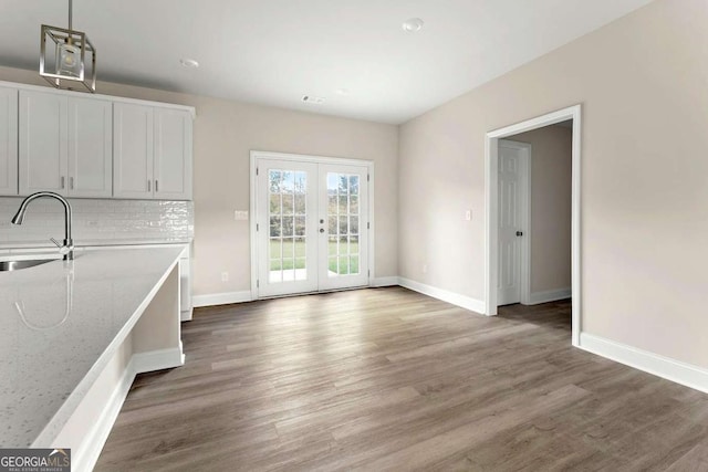 unfurnished dining area with baseboards, french doors, a sink, and wood finished floors