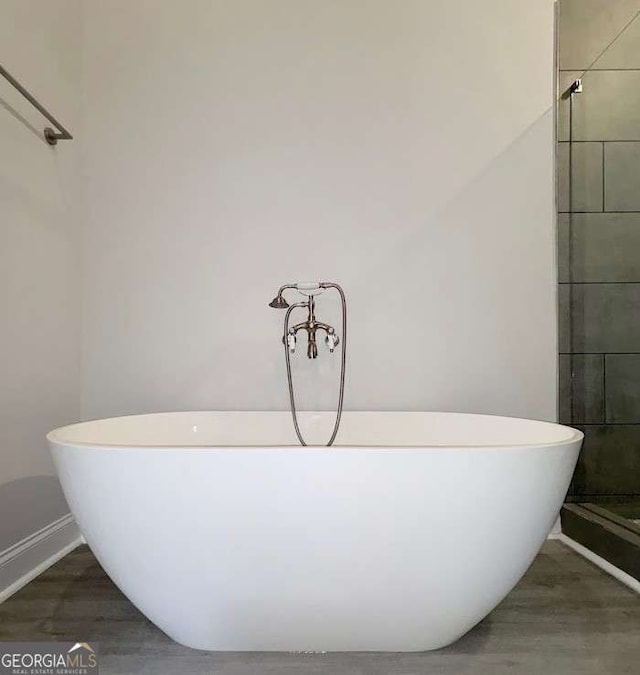 full bathroom featuring a freestanding bath, a shower stall, and wood finished floors