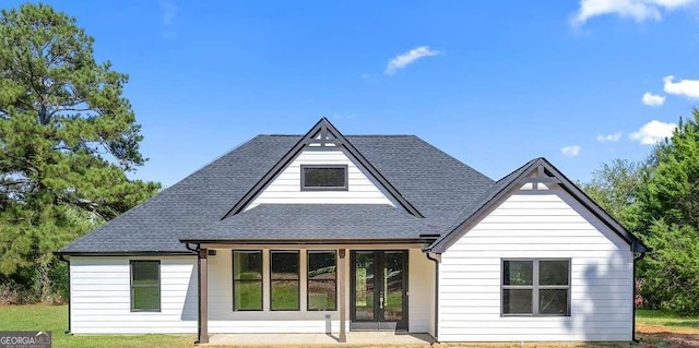 rear view of house featuring a shingled roof and french doors