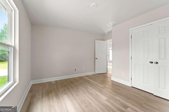 unfurnished bedroom with light wood-type flooring, multiple windows, and baseboards