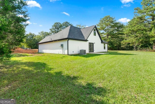 view of side of property with central AC and a yard