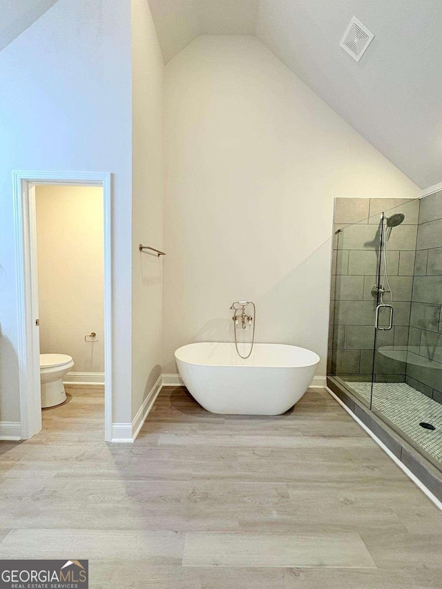 full bathroom featuring a stall shower, visible vents, a freestanding bath, and wood finished floors