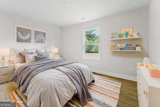 bedroom featuring baseboards, visible vents, and wood finished floors