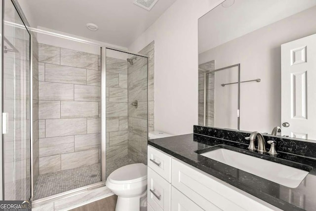 bathroom with toilet, a shower stall, visible vents, and vanity