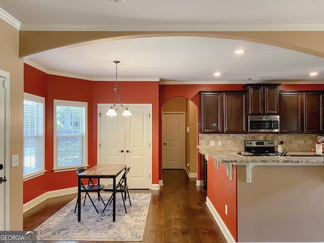 kitchen with tasteful backsplash, a breakfast bar area, hanging light fixtures, stainless steel appliances, and light stone countertops