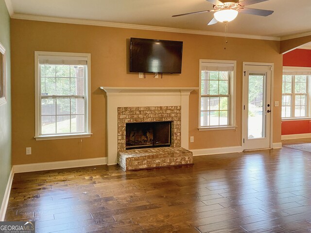 unfurnished living room with ornamental molding, a brick fireplace, dark wood-type flooring, and ceiling fan