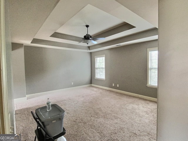 carpeted spare room featuring a raised ceiling and ceiling fan