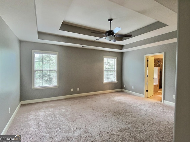 carpeted empty room featuring a tray ceiling and ceiling fan