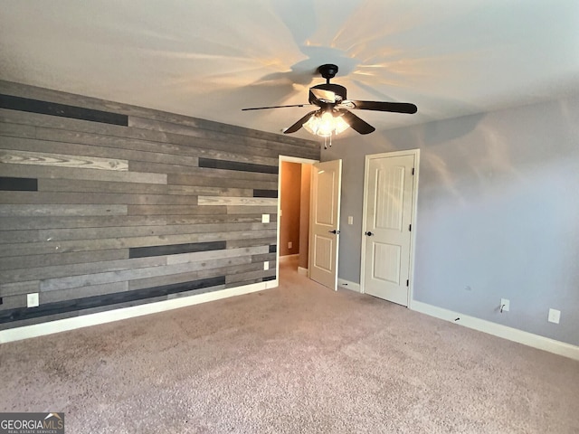 carpeted empty room featuring ceiling fan and wooden walls