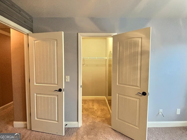 unfurnished bedroom featuring a walk in closet, light colored carpet, and a closet