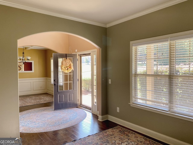 entrance foyer with a notable chandelier, dark wood-type flooring, and ornamental molding