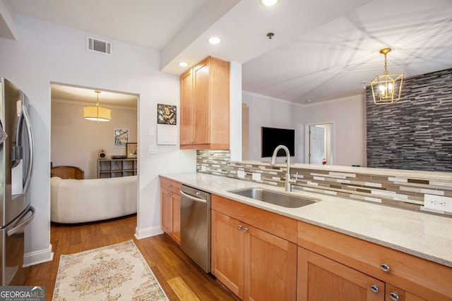 kitchen with sink, appliances with stainless steel finishes, tasteful backsplash, decorative light fixtures, and light wood-type flooring