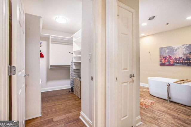 bathroom with hardwood / wood-style flooring and a tub to relax in