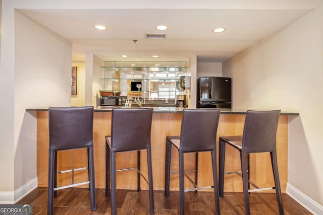 bar with hardwood / wood-style flooring and black appliances