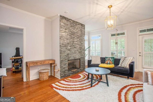 living room with a fireplace, wood-type flooring, ornamental molding, and a chandelier