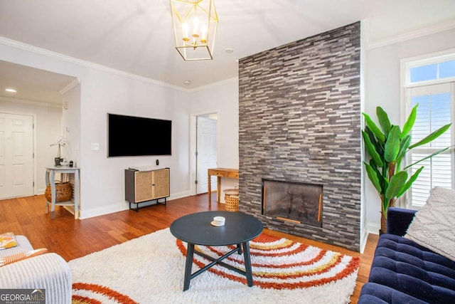 living room with crown molding, hardwood / wood-style flooring, a fireplace, and an inviting chandelier