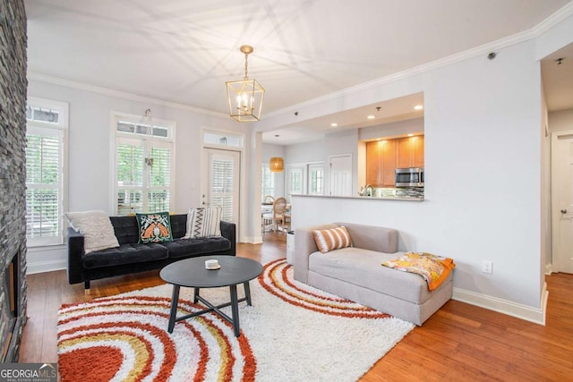 living room featuring ornamental molding, wood-type flooring, and a notable chandelier