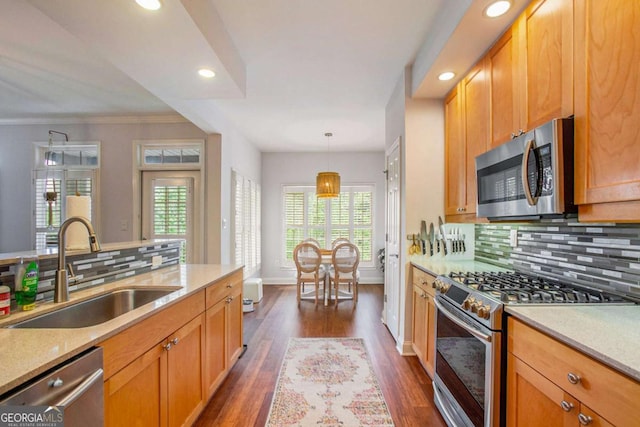 kitchen with sink, appliances with stainless steel finishes, dark hardwood / wood-style floors, pendant lighting, and decorative backsplash