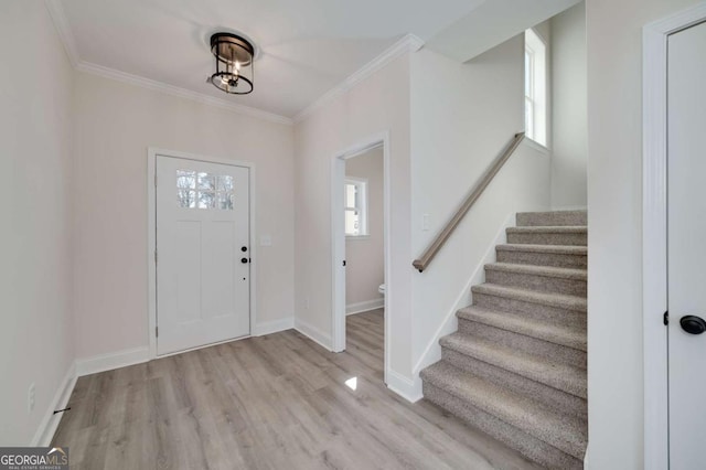 entryway with ornamental molding and light hardwood / wood-style floors