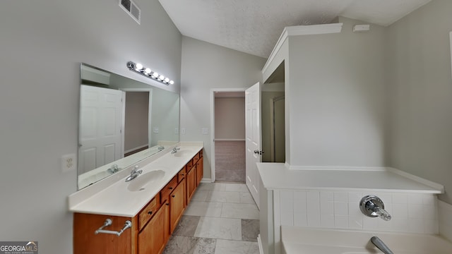 bathroom with vanity, a bath, vaulted ceiling, and a textured ceiling