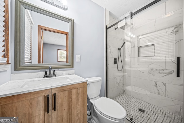 bathroom featuring vanity, toilet, a textured ceiling, and a shower with shower door