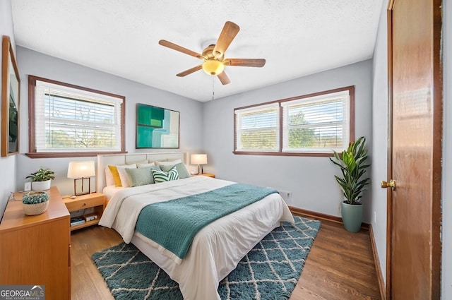 bedroom featuring dark wood-type flooring, ceiling fan, and a textured ceiling