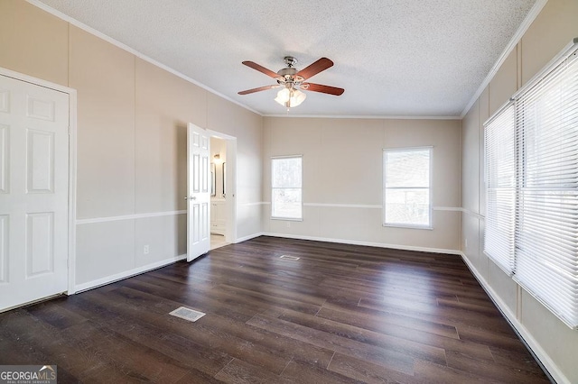 spare room with ceiling fan, dark wood-type flooring, ornamental molding, and a textured ceiling