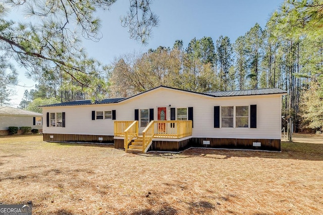 manufactured / mobile home with a wooden deck and a front lawn