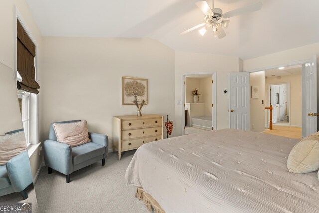 bedroom with ceiling fan, lofted ceiling, ensuite bathroom, and light carpet