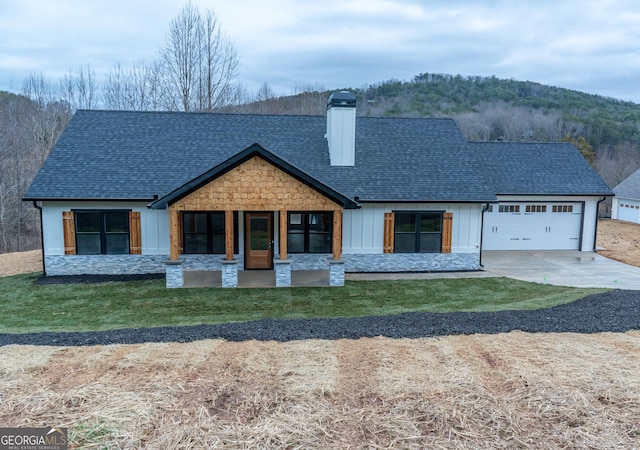 view of front of home with a garage, covered porch, and a front lawn