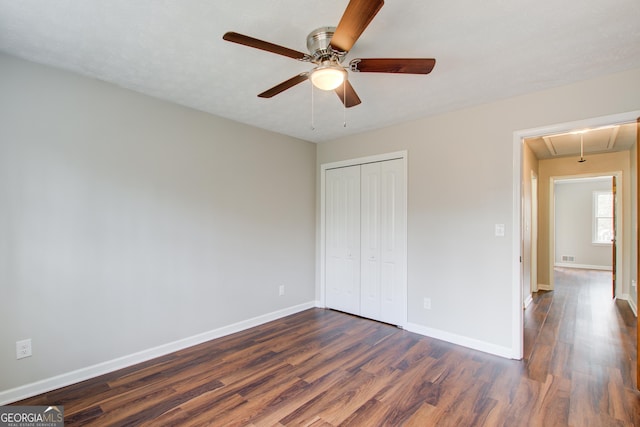 unfurnished bedroom with dark wood-type flooring, ceiling fan, and a closet