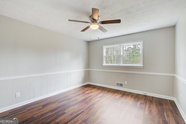 empty room with ceiling fan, dark wood-type flooring, and a textured ceiling