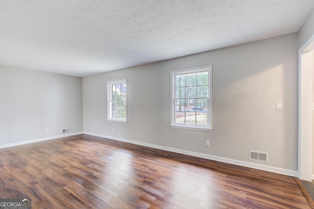 unfurnished room with dark wood-type flooring and a textured ceiling