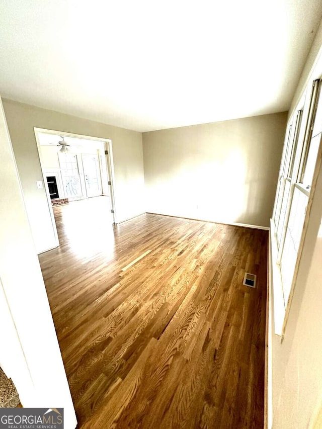 empty room with hardwood / wood-style floors and ceiling fan