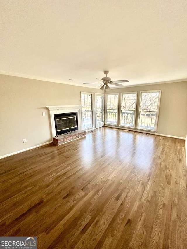 unfurnished living room featuring hardwood / wood-style floors, a fireplace, ceiling fan, and plenty of natural light