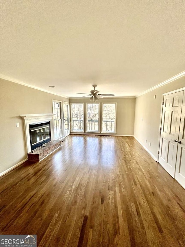 unfurnished living room with a brick fireplace, crown molding, hardwood / wood-style floors, and ceiling fan