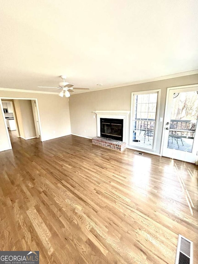 unfurnished living room with ceiling fan, wood-type flooring, a fireplace, and ornamental molding