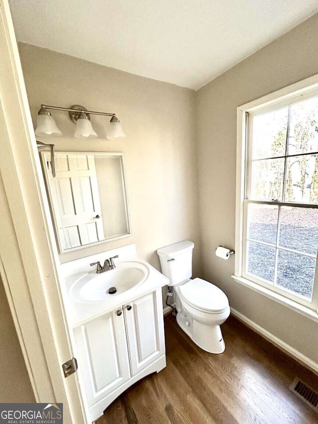 bathroom with vanity, hardwood / wood-style flooring, plenty of natural light, and toilet