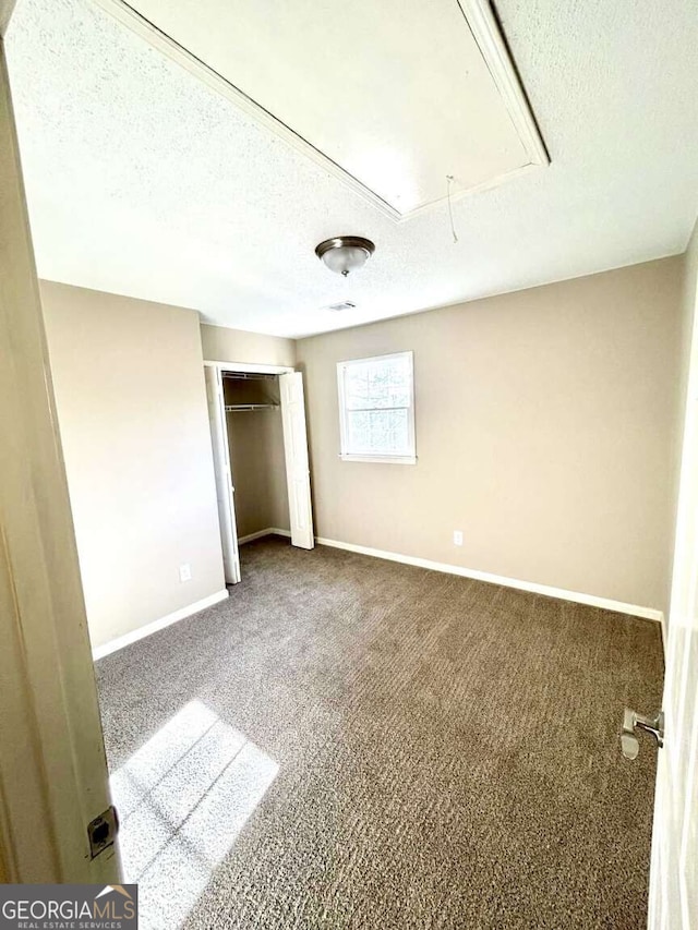 unfurnished bedroom featuring carpet, a textured ceiling, and a closet