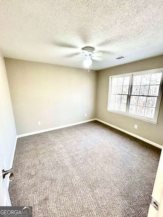 spare room with a textured ceiling, ceiling fan, and carpet flooring