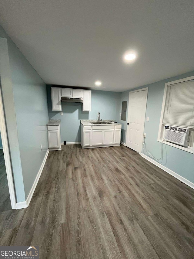 washroom with cooling unit, dark hardwood / wood-style flooring, electric panel, and sink