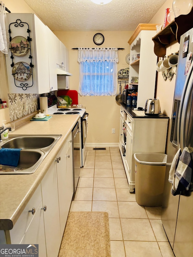 kitchen featuring white cabinetry, sink, light tile patterned floors, and a textured ceiling