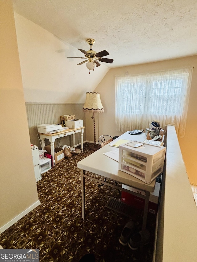 carpeted home office with ceiling fan, lofted ceiling, and a textured ceiling