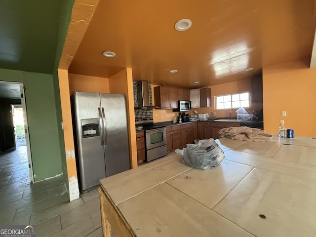 kitchen featuring stainless steel appliances, sink, kitchen peninsula, and wall chimney exhaust hood