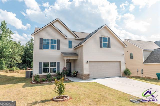 view of front of home with a garage, central AC, and a front yard