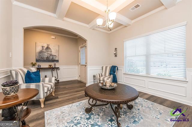 living area featuring dark hardwood / wood-style floors, coffered ceiling, beam ceiling, and a chandelier