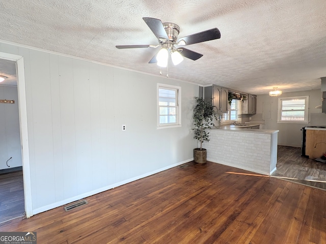 unfurnished living room featuring ornamental molding, dark hardwood / wood-style floors, and a textured ceiling