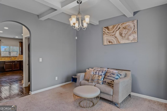 living area featuring carpet floors, an inviting chandelier, and beam ceiling