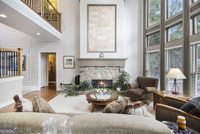 living room with wood-type flooring, a towering ceiling, and a fireplace